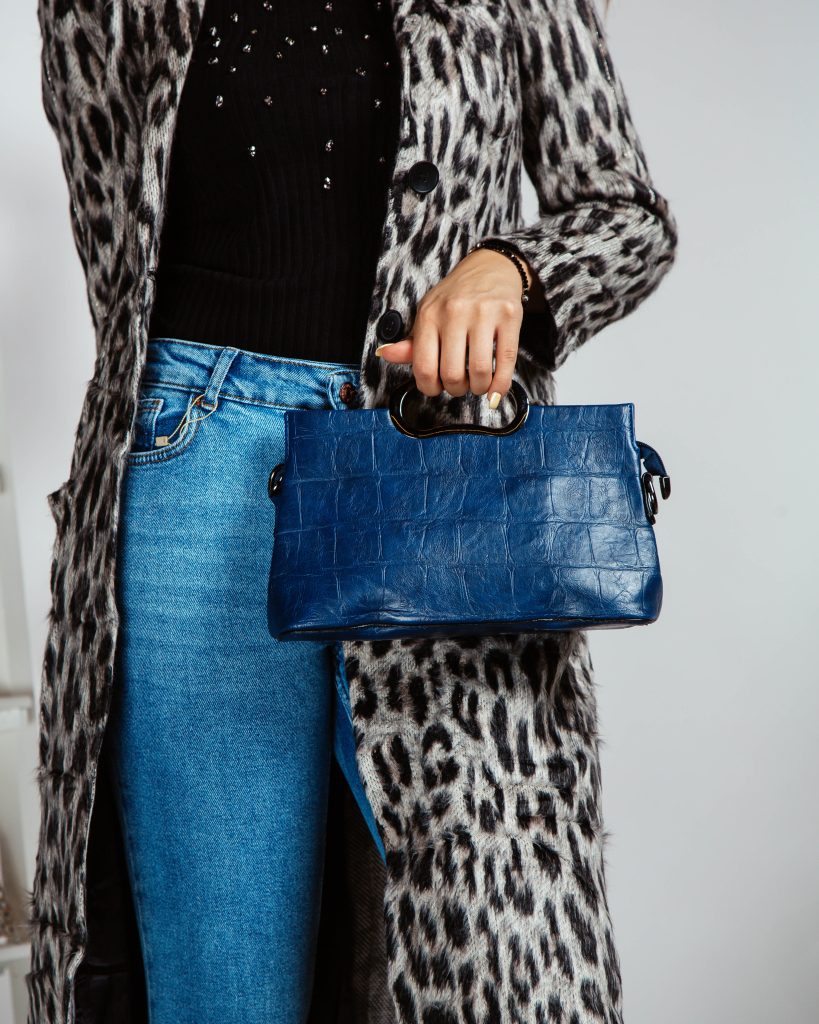 woman jeans black top leopard print cardigan holding navy blue bag